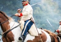 Men in historical military uniforms riding horses