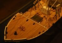 Model of a wooden ship's deck with railings.