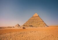 a group of people riding horses in front of a pyramid