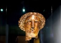 Ancient bronze bust of a woman with curly hair.