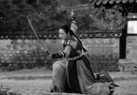 grayscale photo of woman holding sword