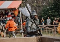 Knight in armor holding a polearm at a historical reenactment.