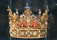 A royal golden crown displayed in a case.