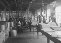 a black and white photo of people working in a factory