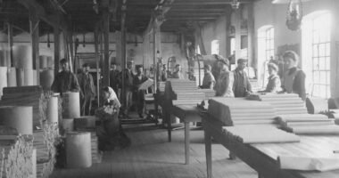 a black and white photo of people working in a factory
