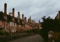 Row of historic buildings with tall chimneys under cloudy sky