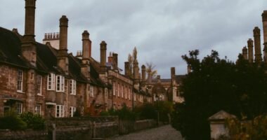 Row of historic buildings with tall chimneys under cloudy sky