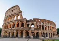 a large stone building with Colosseum in the background