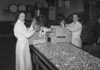 two women in white coats are opening a box